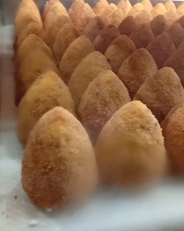 Arancini appena fritti in fila nella vetrina della rosticceria