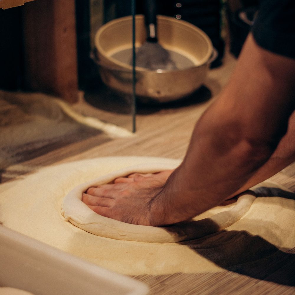 Le mani di un pizzaiolo che stendono l'impasto